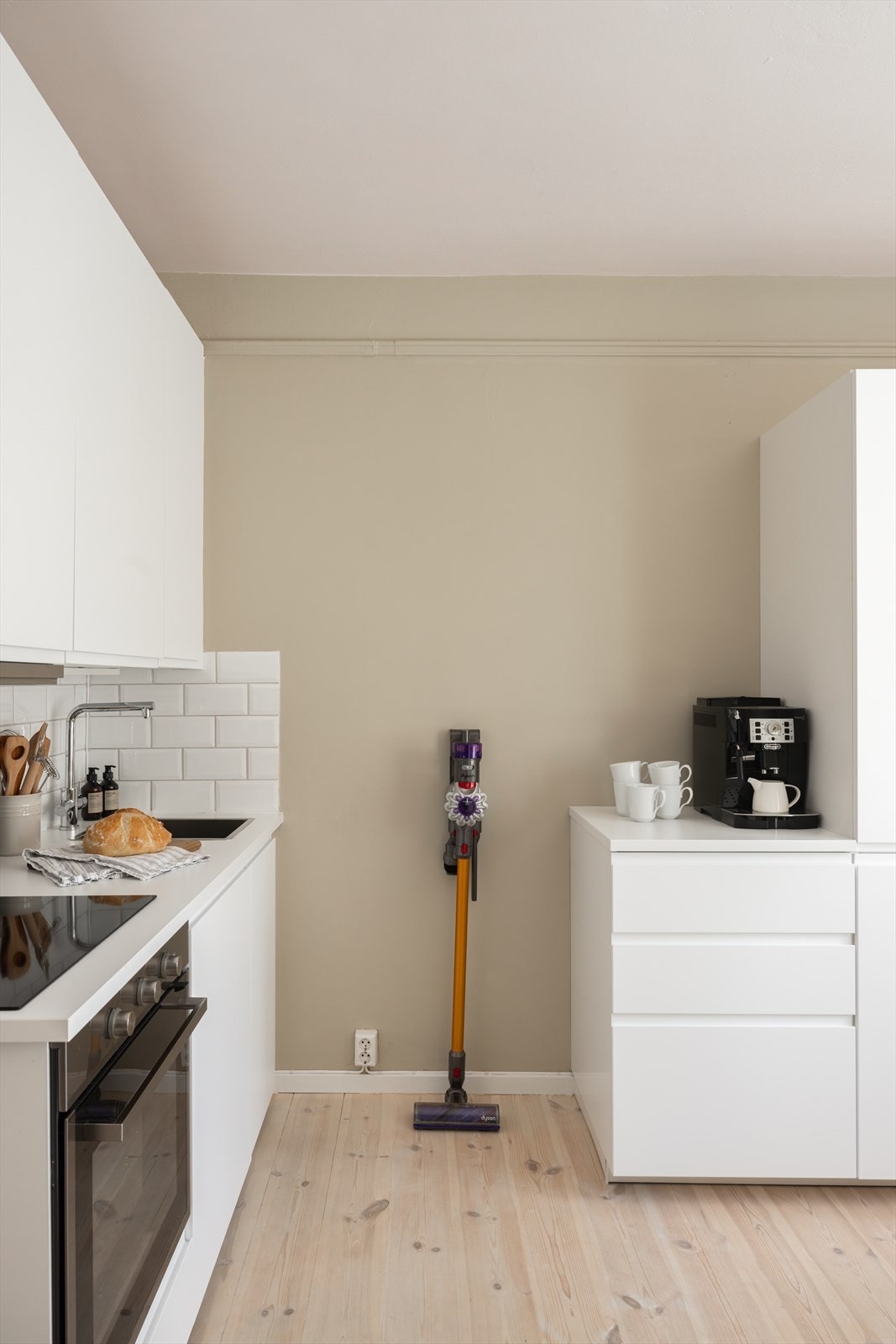 En stilren, hvit kjøkkeninnredning med benkeplate av laminat og nedfelt oppvaskkum. Galleribilde