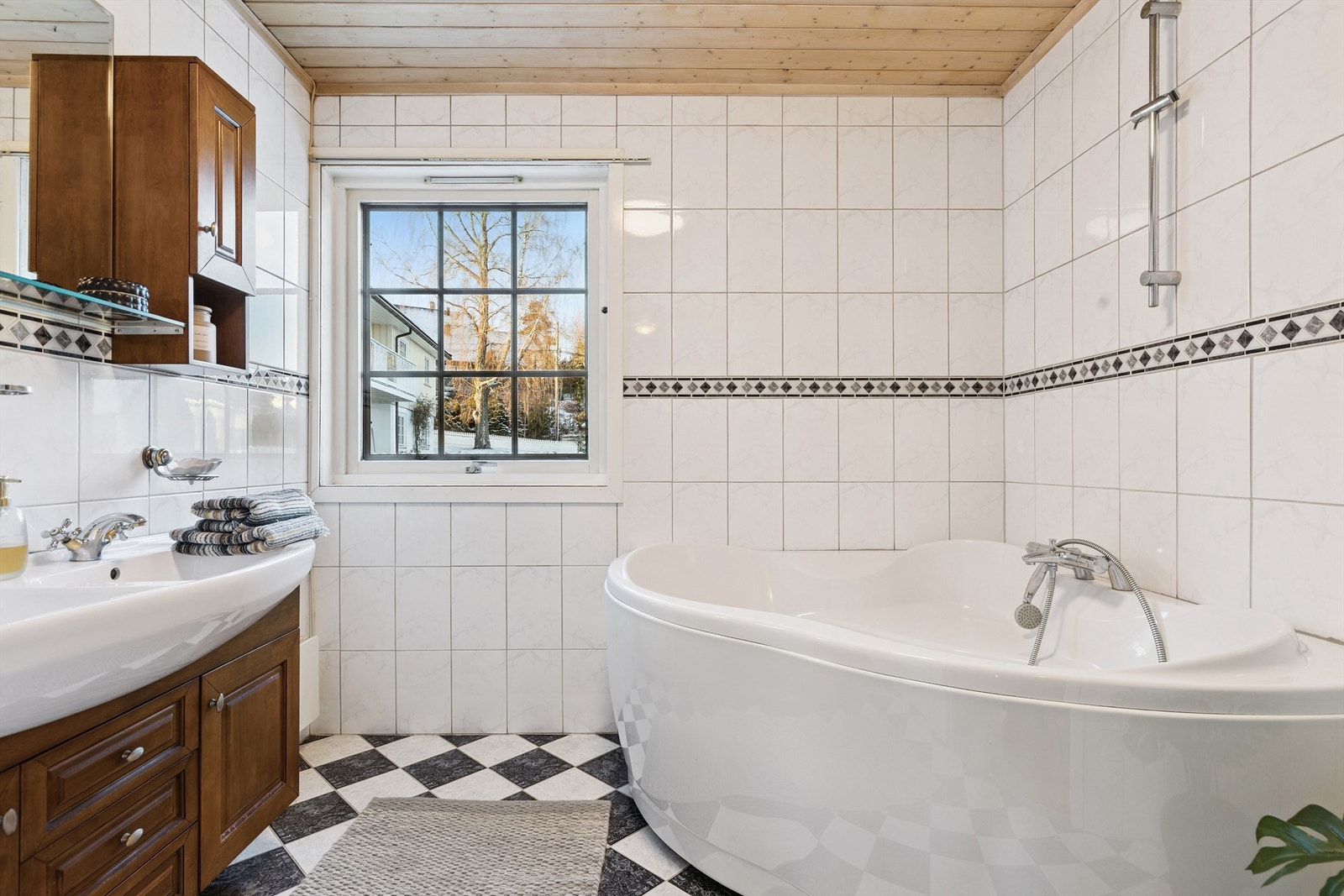 Bad i del 1: Badet har flislagt gulv, flislagte vegger og en himling med trepanel og belysning. Det inneholder et vegghengt servantskap med en dobbelt overliggende servant og to-greps armaturer. Galleribilde