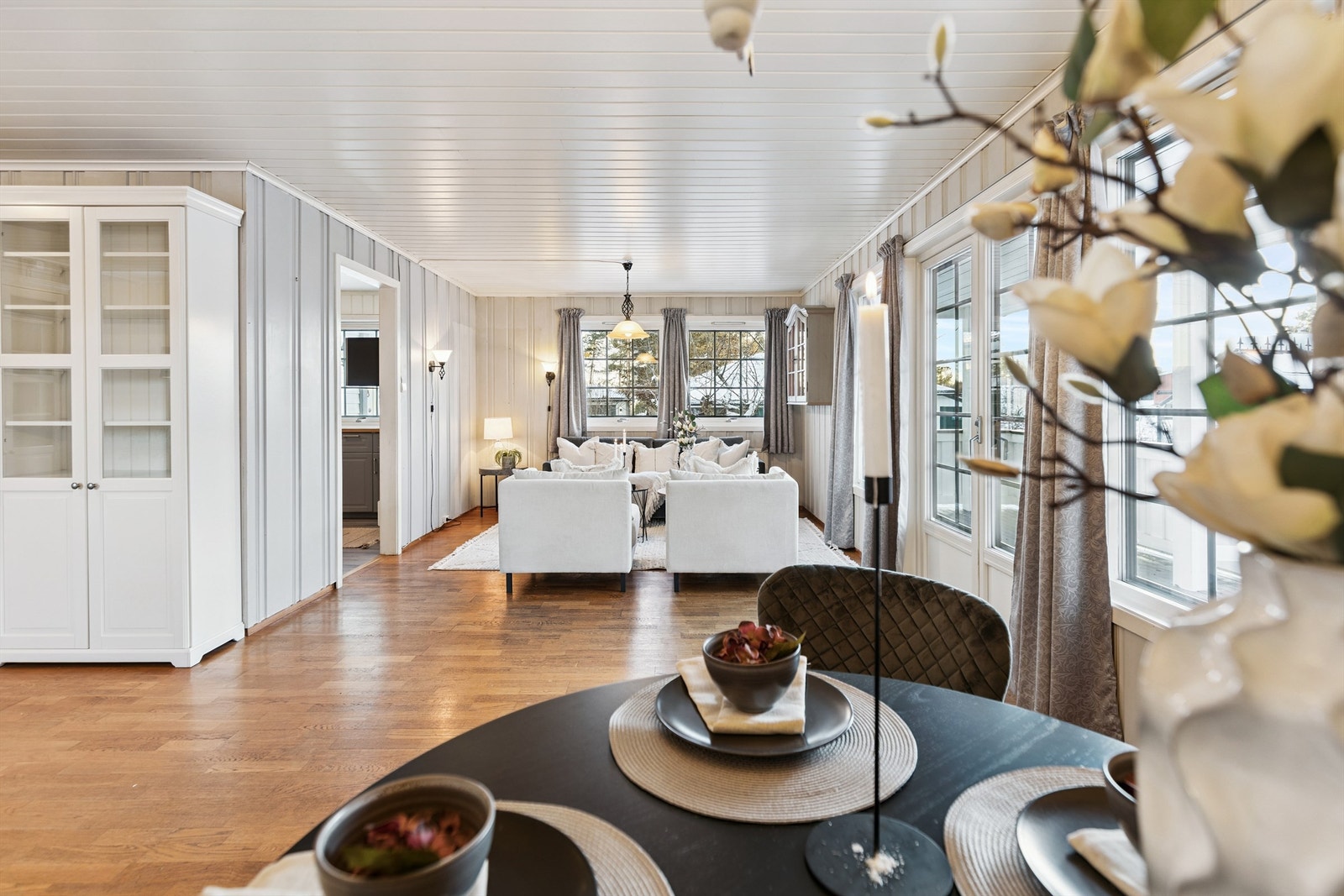 Sammenføyingen av boligen har skapt en svært fleksibel og romslig bolig med mange muligheter. Bildene vil nå vise boligens del 1. Her fra stuen med utgang til hage, drivhus og stabbur. Galleribilde