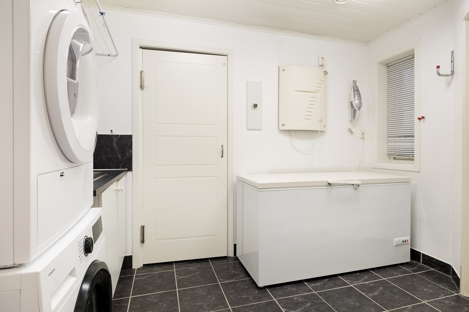 Praktisk vaskerom av god storleik med flis på golv og måla veggar. Frå vaskerommet er det tilkomst til kjøkken via ein liten gang samt direkte tilkomst ut til garasjen. Galleribilde