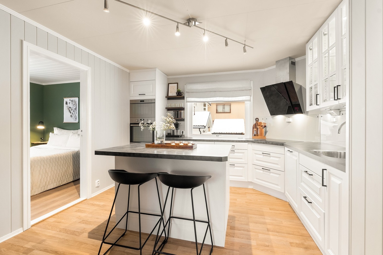 Kjøkken med hvite profilerte fronter, integrert komfyr og oppvaskmaskin - svært god skap- og benkeplass! Galleribilde