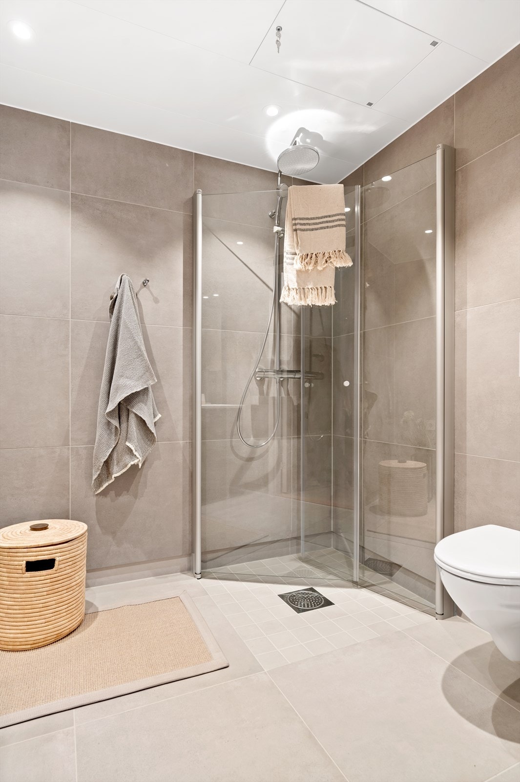 Badet er innredet med vegghengt toalett og dusjhjørne med regnfallsdusj og innfellbare dører i herdet glass. Galleribilde