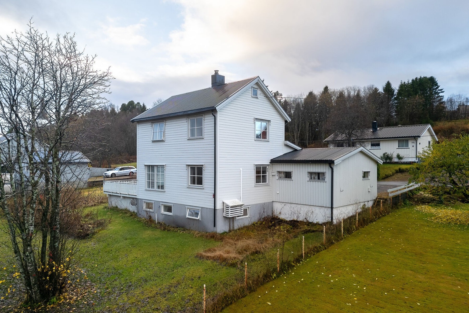 Fasade og uteområde. Tomten er opparbeidet med plen, busker og trær. Galleribilde