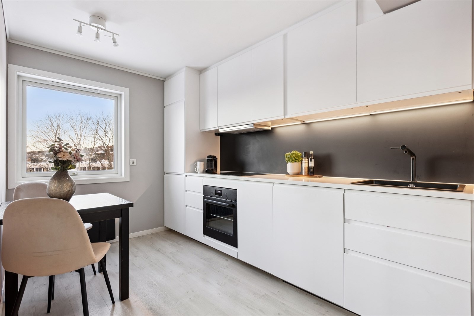 Kjøkkeninnredning fra 2020 med slette fronter og benkeplate i laminat. Det er integrert platetopp, stekeovn, kombinert kjøl og fryseskap og oppvaskmaskin. Galleribilde