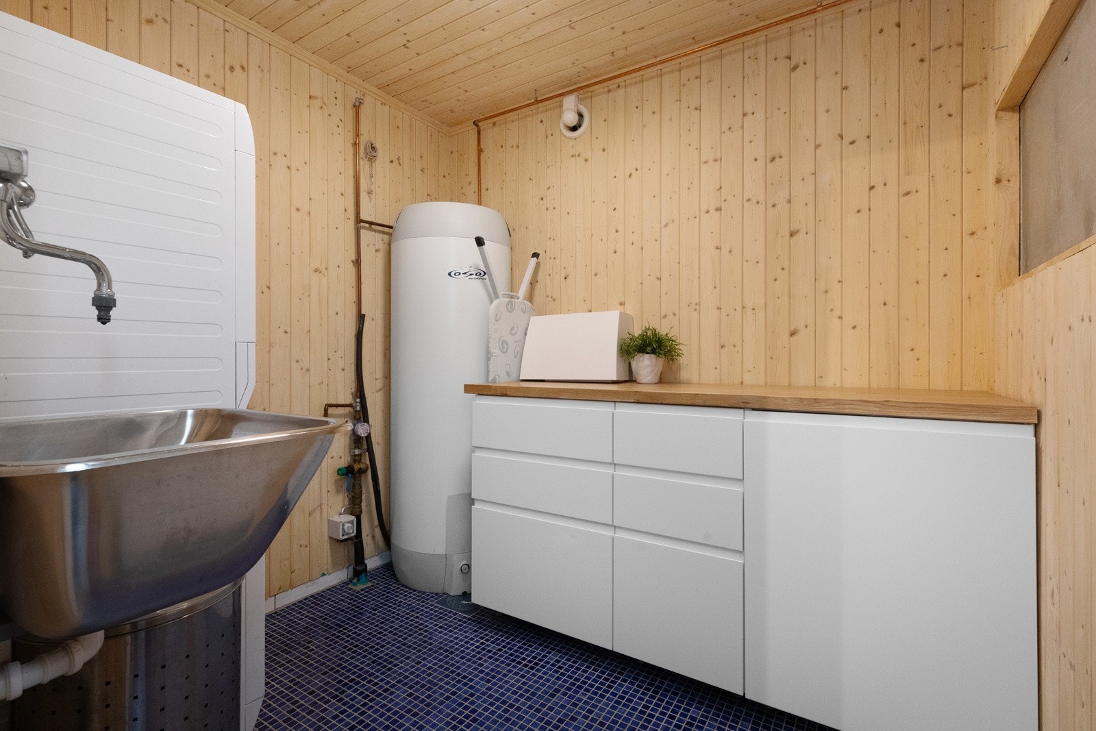 Vaskerom med tekniske installasjoner. Gulv med blå mosaikk og varmekabler. Nyere innredning med god oppbevaringsplass Galleribilde