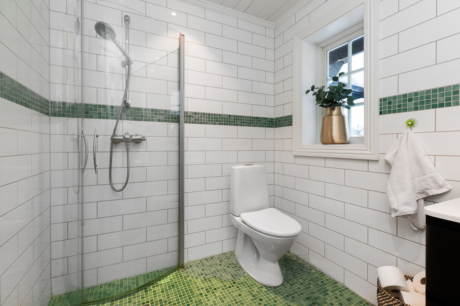 Baderommet har hvite fliser på vegg og grønne mosaikk på gulv Galleribilde