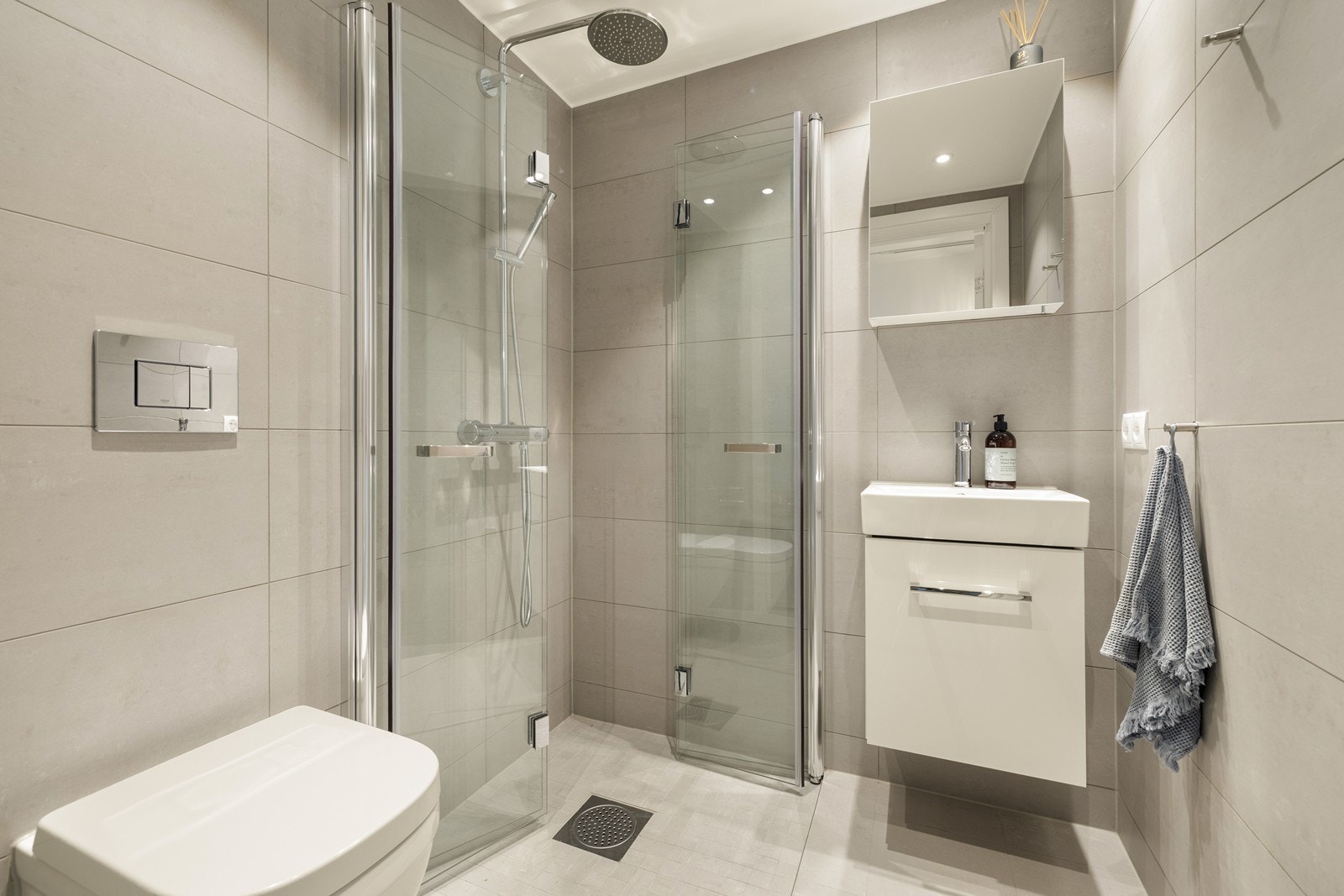 Lyst og praktisk bad som er innredet med vegghengt toalett og dusjhjørne. Galleribilde