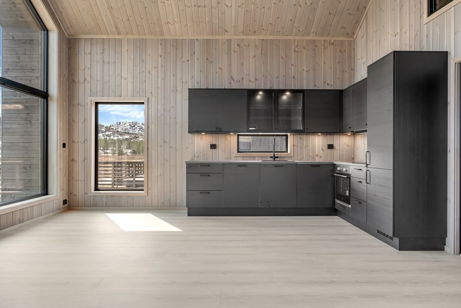 Lekkert kjøkken bestående av integrerte hvitevarer, nedfelt vask og platetopp. Galleribilde