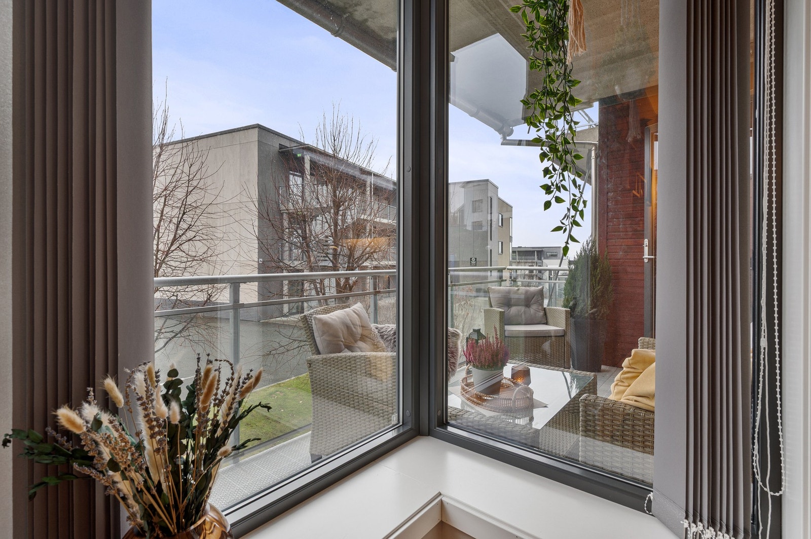 Store hjørnevinduer gir rikelig med naturlig lys og en luftig overgang mellom stue og balkong. Galleribilde