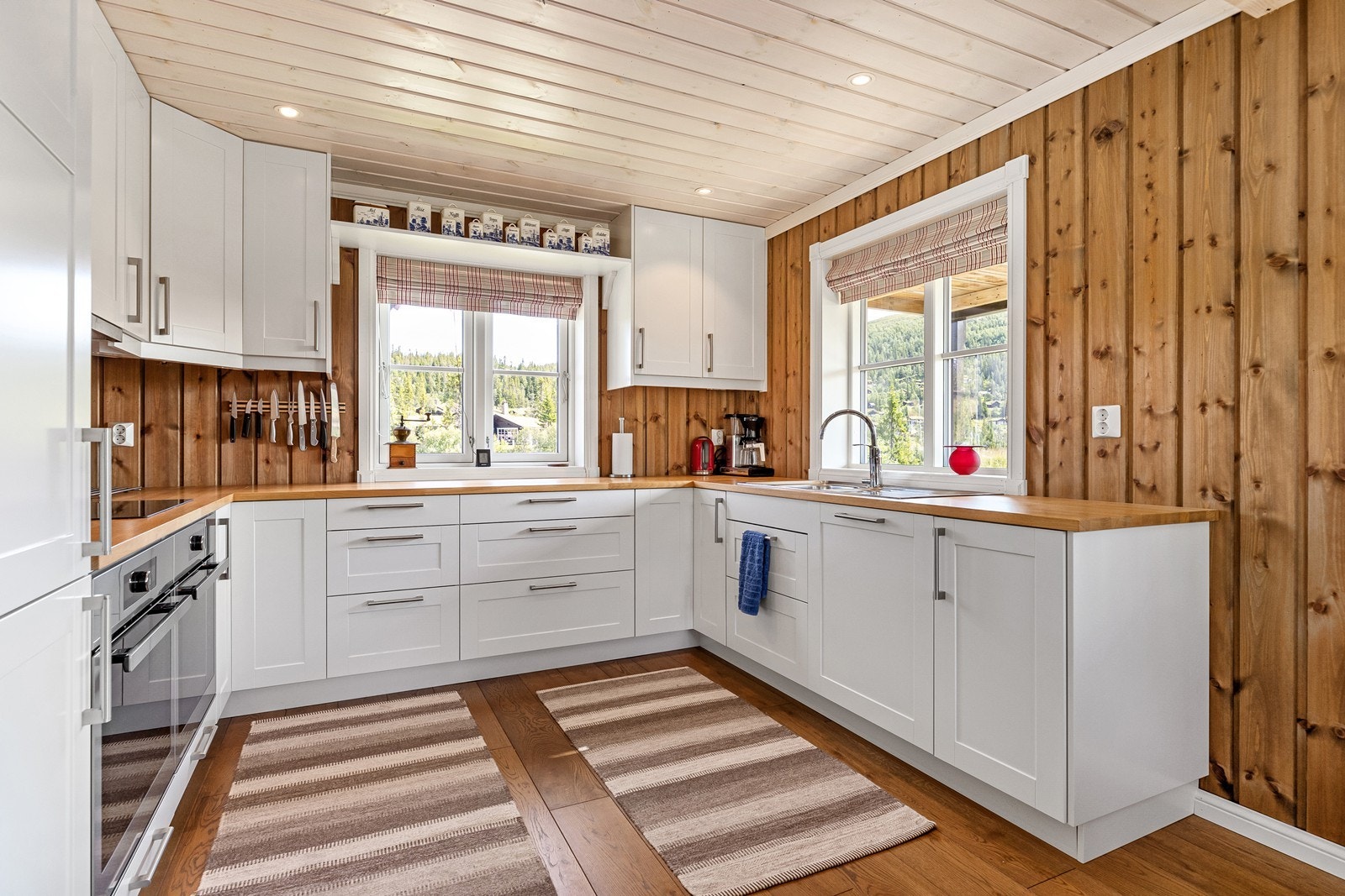 Kjøkkenet er med lyse fronter, benkeplate i heltre og integrerte hvitevarer. Her finner du kjøleskap med fryser, to komfyrer, platetopp og oppvaskmaskin Galleribilde