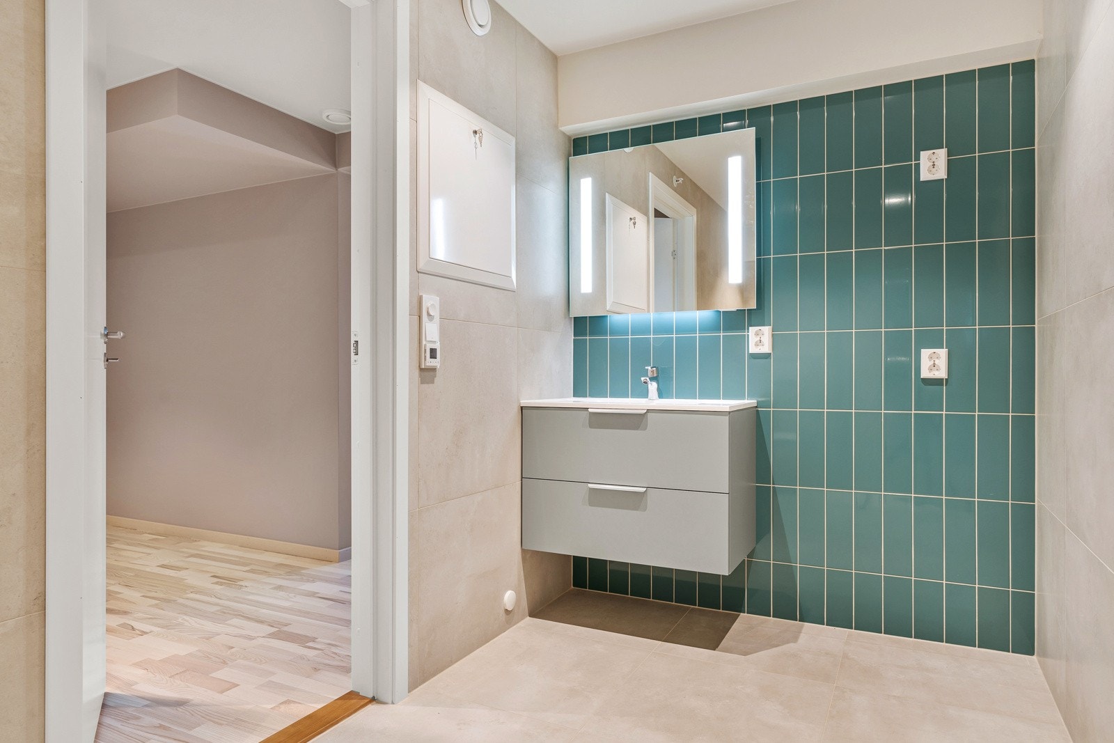 Badet er innredet med vegghengt toalett, dusjhjørne med innfellbare dører, opplegg for vaskemaskin og en pen innredning med nedfelt servant og skuffeseksjoner. Galleribilde