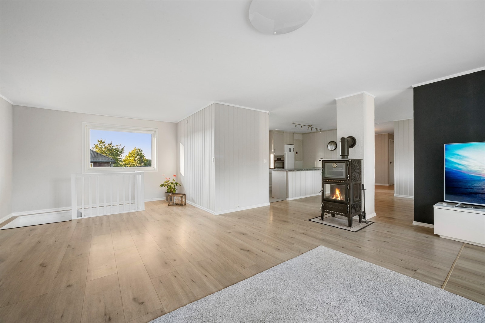 Midt i stuen står en sjarmerende peisovn som bidrar med koselig stemning og varme på kjølige dager Galleribilde