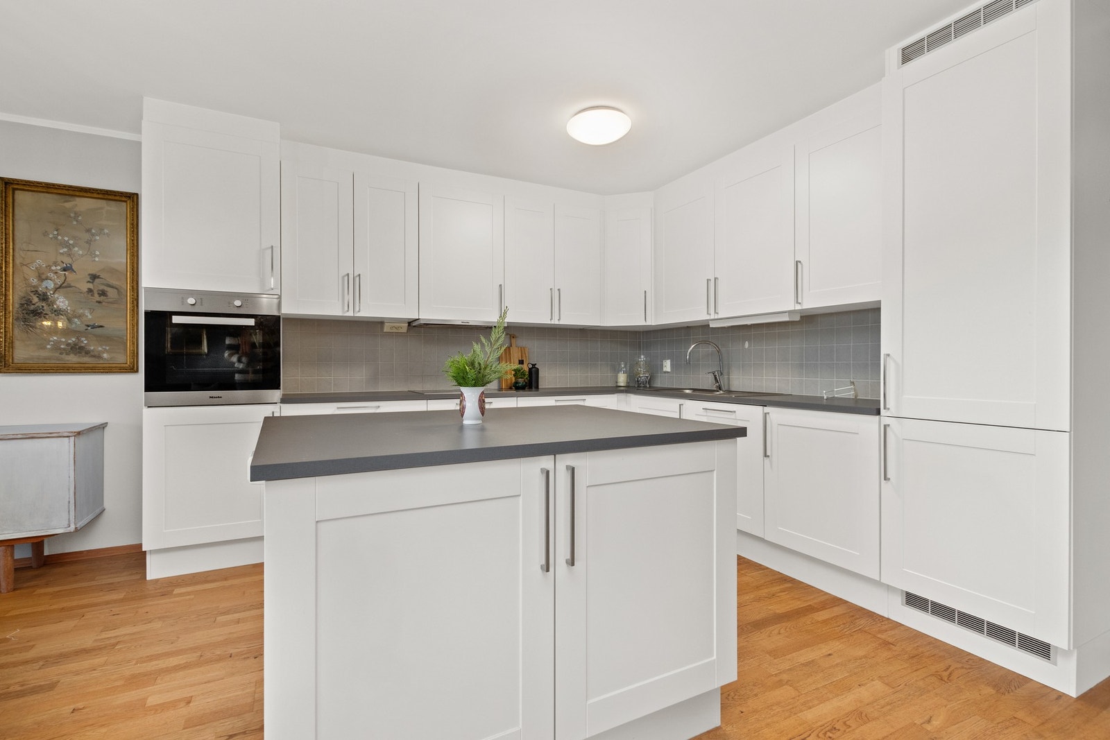 Romslig kjøkken med Miele hvitevarer og kjøkkenøy. Galleribilde