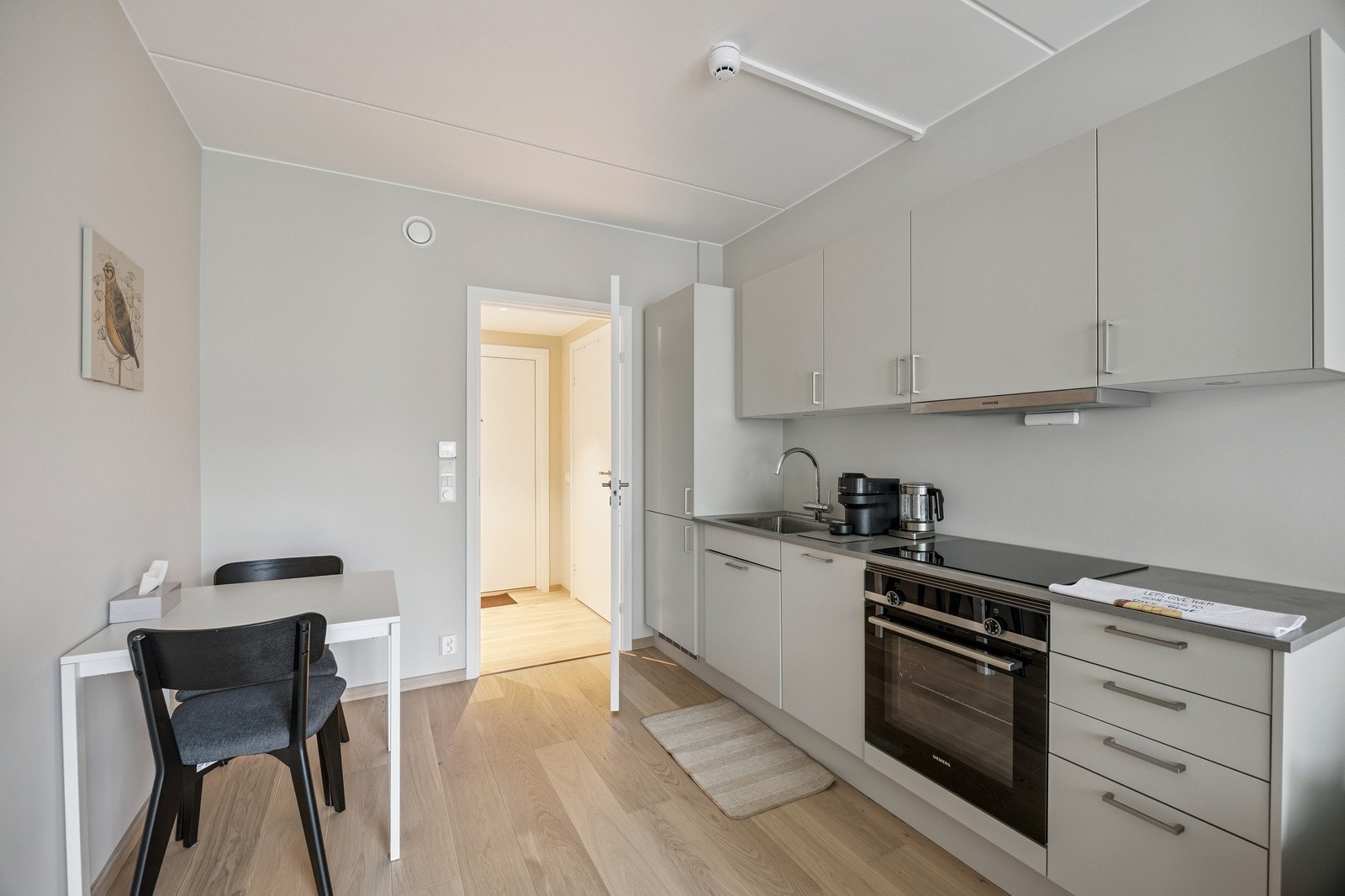 Kjøkken med integrerte hvitevarer og bord med plass til 2 stoler. Galleribilde