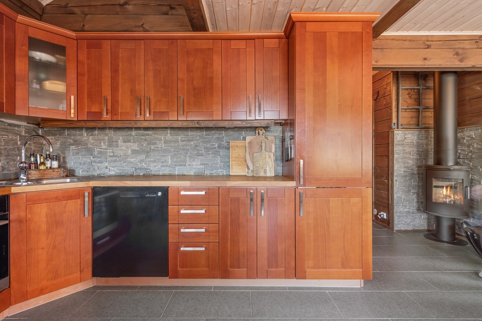 Romslig kjøkkenbenk med fine steindetaljer som underbygger den lune logdestilen som passer så godt til fjells. Galleribilde