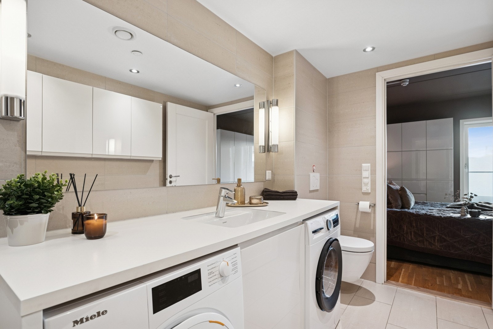 Badet er fra byggeår med fliser, gulvvarme, downlights, servantinnredning, dusjhjørne med regndusj, vegghengt toalett og opplegg for vaskemaskin. Galleribilde