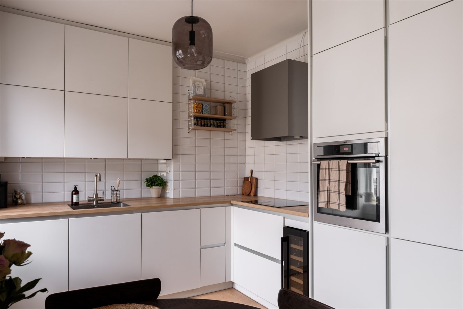 Stilrent Kvik-kjøkken fra 2017 med tidløse slette fronter, laminat benkeplate og fliser over benkeplaten. Galleribilde