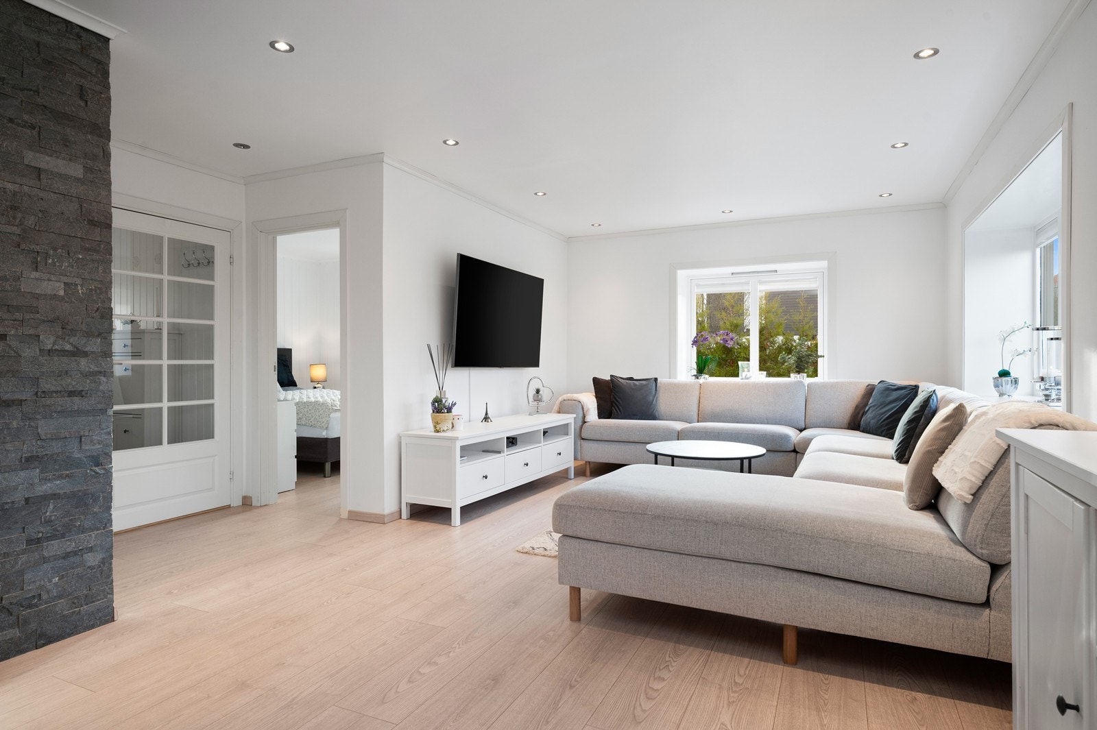 En fondvegg i skiferstein gir stuen karakter. Døren fører inn til et av soverommene. Galleribilde