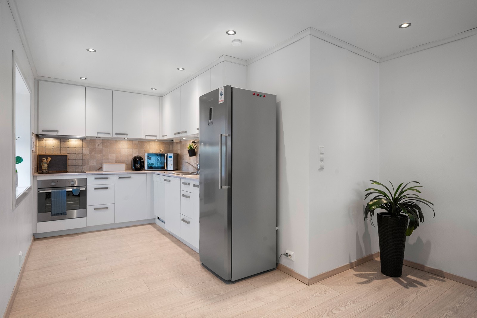 Kjøkkenet har en praktisk L-form, med overskap som går helt opp mot taket, hvor det er god lagringsplass. Galleribilde