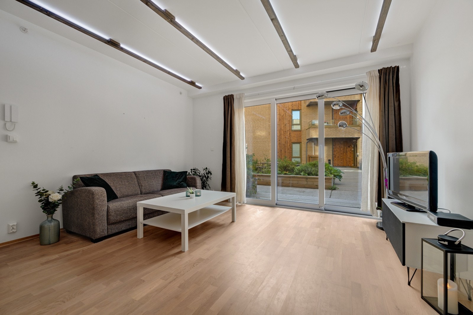 Her er det plass til sofaseksjon og et lite spisebord hvor man kan nyte måltider med deilig dagslys fra de store glassdørene Galleribilde