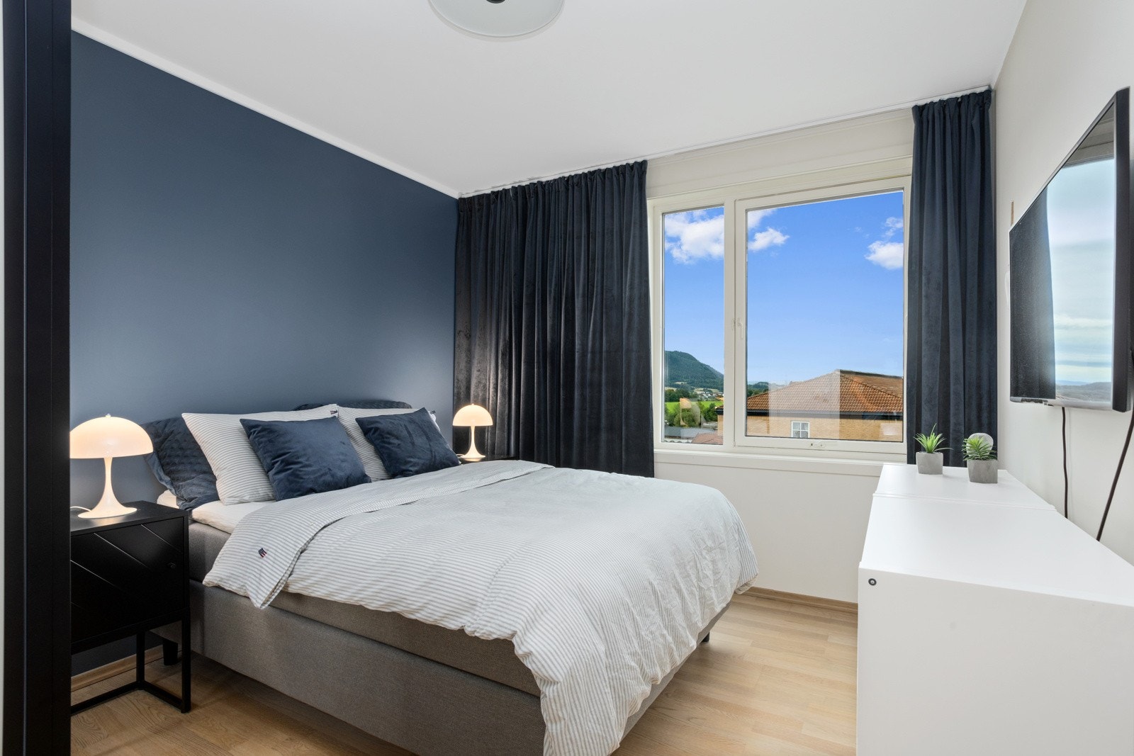 Romslig soverom med skyvedørsgarderobe, plass til en stor seng, nattbord og annet møblement. Galleribilde