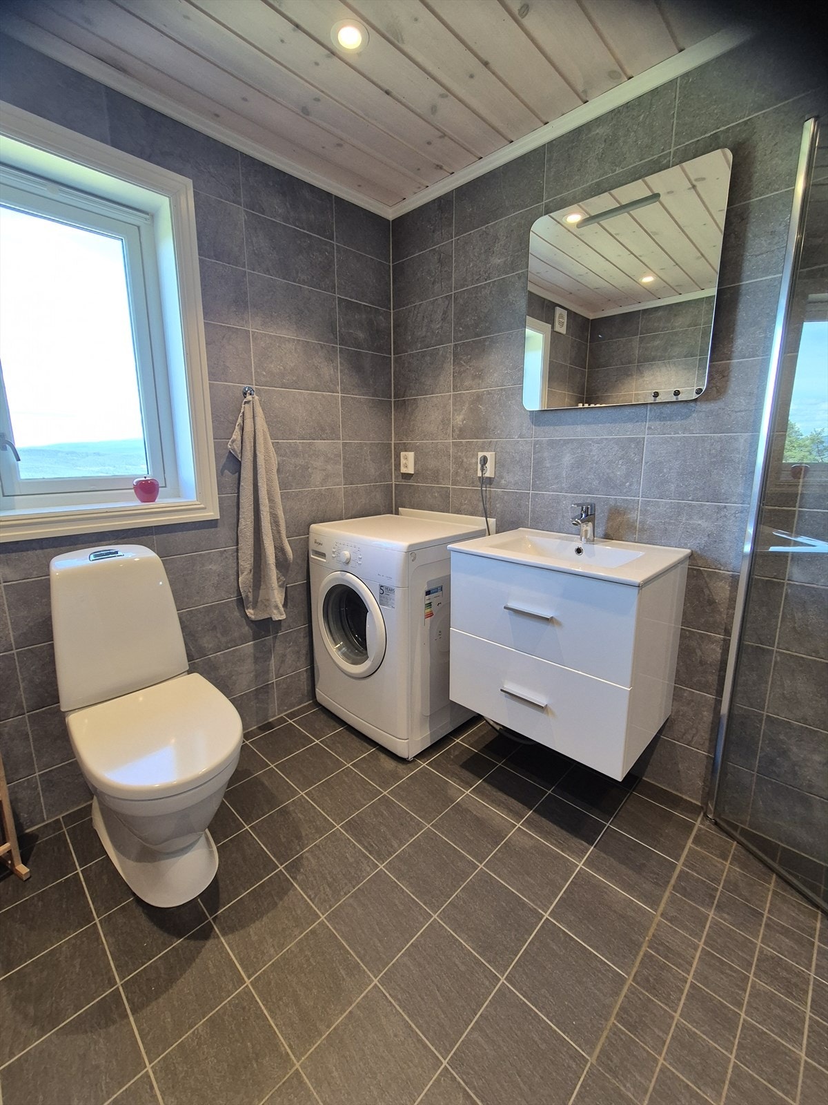 Pent, flislagt bad innredet med servantseksjon med heldekkende servant, dusjhjørne samt toalett. Galleribilde