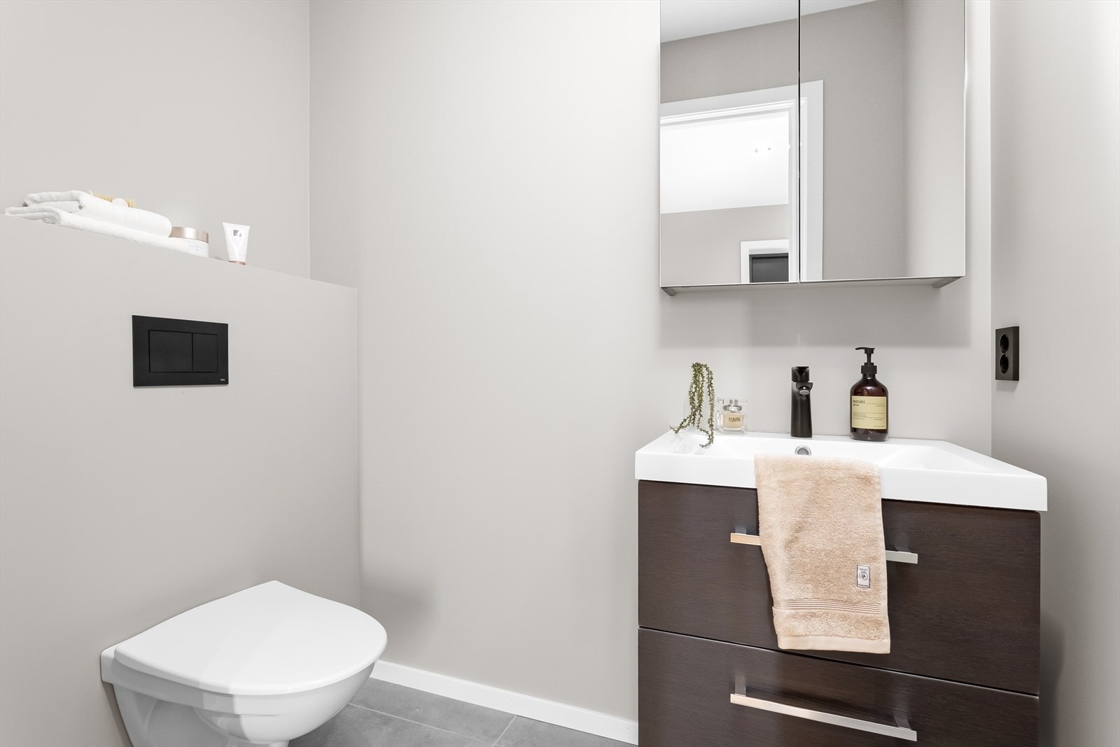 Stilrent toalettrom med heldekkende servant, veggskap med speil og vegghengt toalett. Et ideelt rom for gjester. Galleribilde