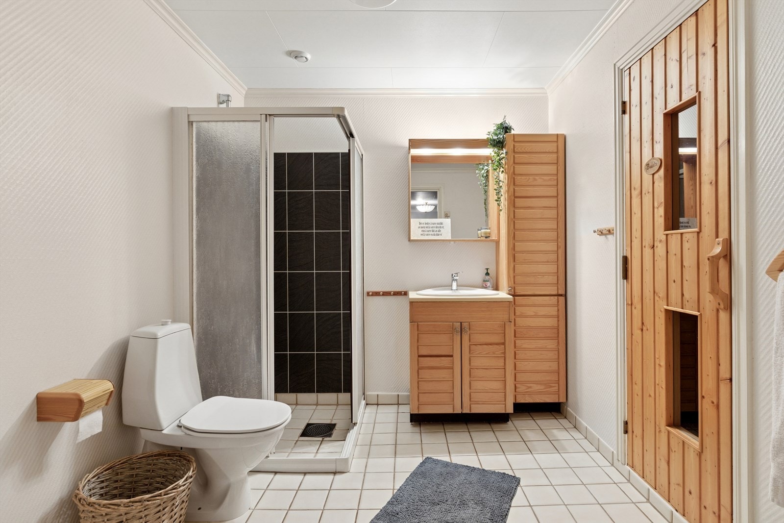 Romslig bad med flislagt gulv med varme og dusjhjørne. Inngang til badstue. Galleribilde