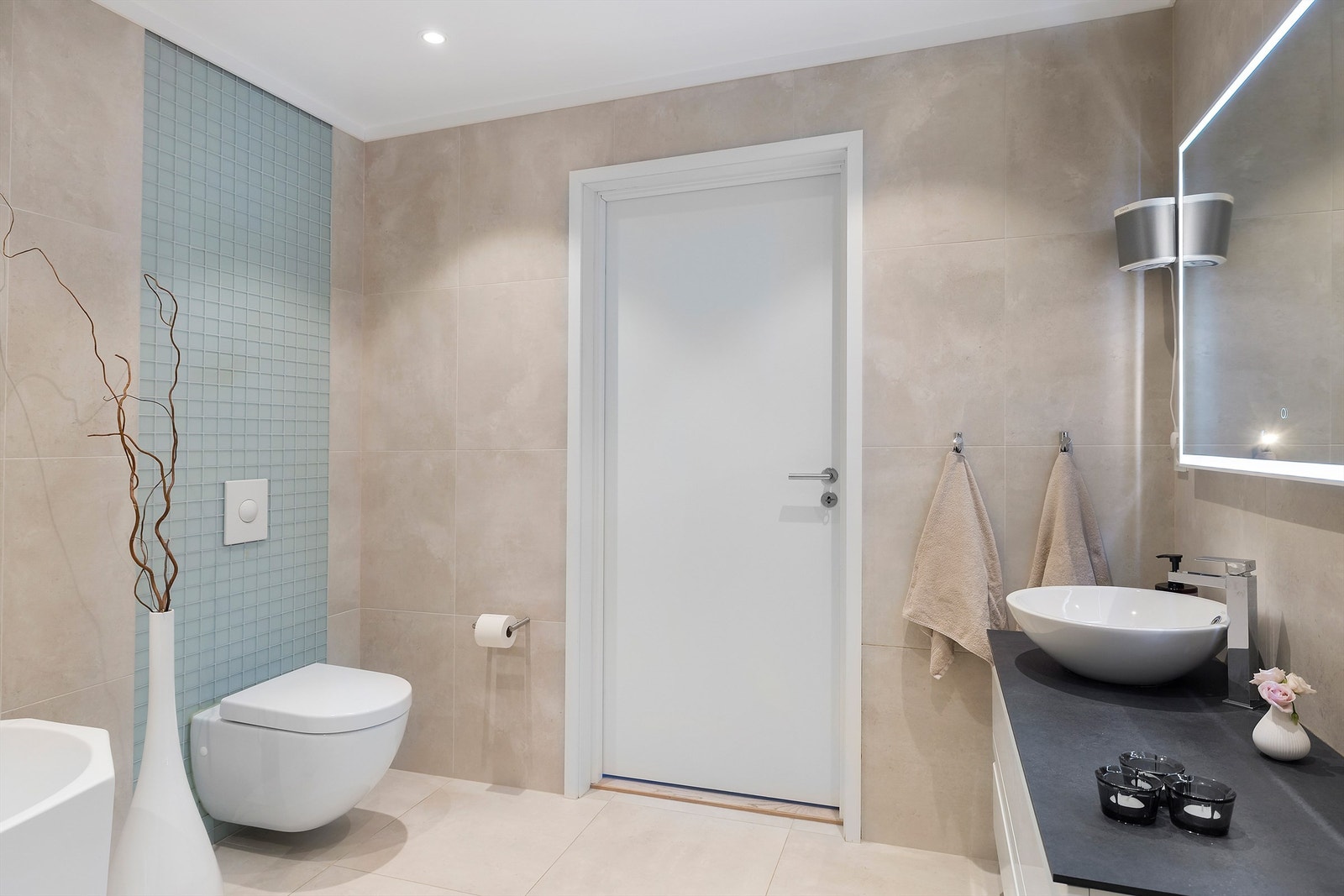 Videre er det speil med integrert lys, dusjhjørne med regn- og hånddusj, samt vegghengt toalett fra Villeroy & Boch. Galleribilde