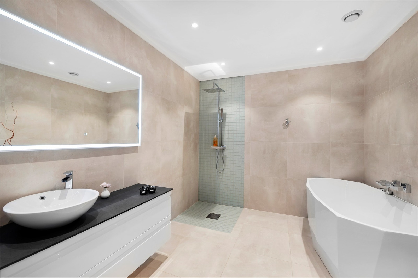 Badet har flislagt gulv med gulvvarme, flislagte vegger og malt, slett himling med downlights. Innredning med slette fronter er levert av Korsbakken, med benkeplate i Corian, toppmontert servant og ett-greps armatur. Galleribilde