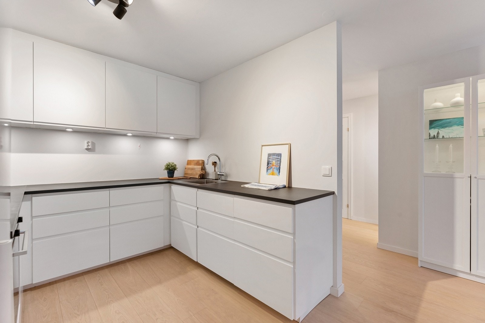 Kjøkkenet består av slette hvite fronter, svart benkeplate og rikelig med oppbevaringsplass. Galleribilde