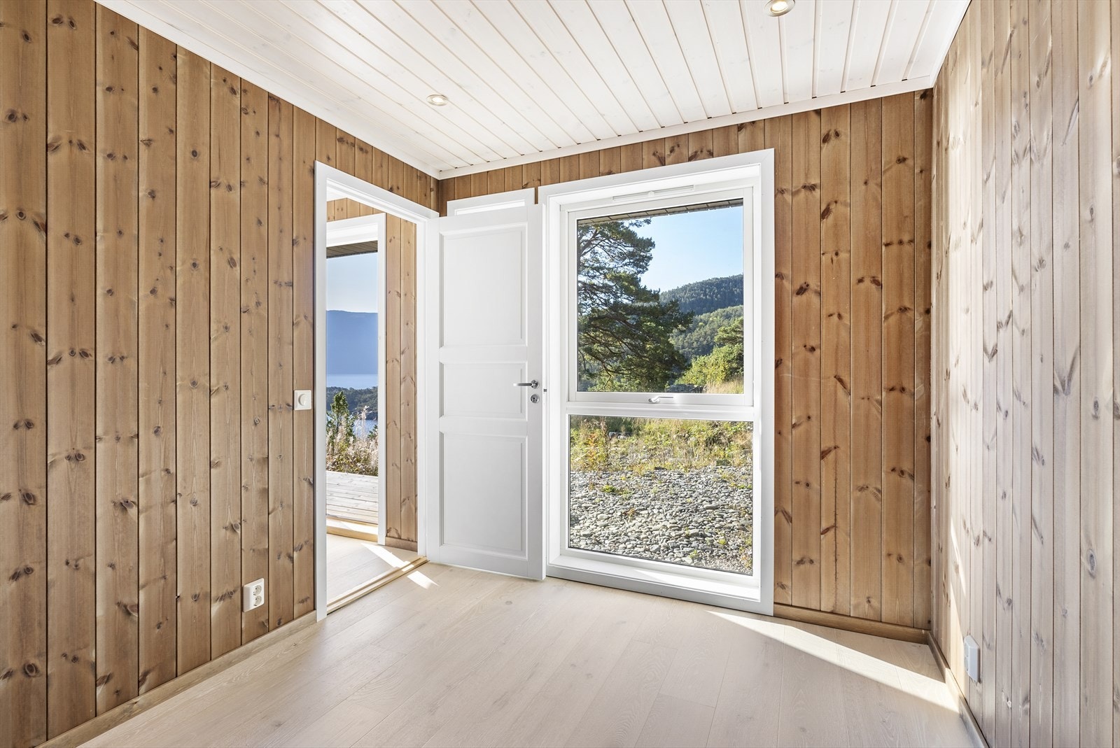 Hytten har panel på vegger og i tak, og pen eikeparkett på gulv Galleribilde