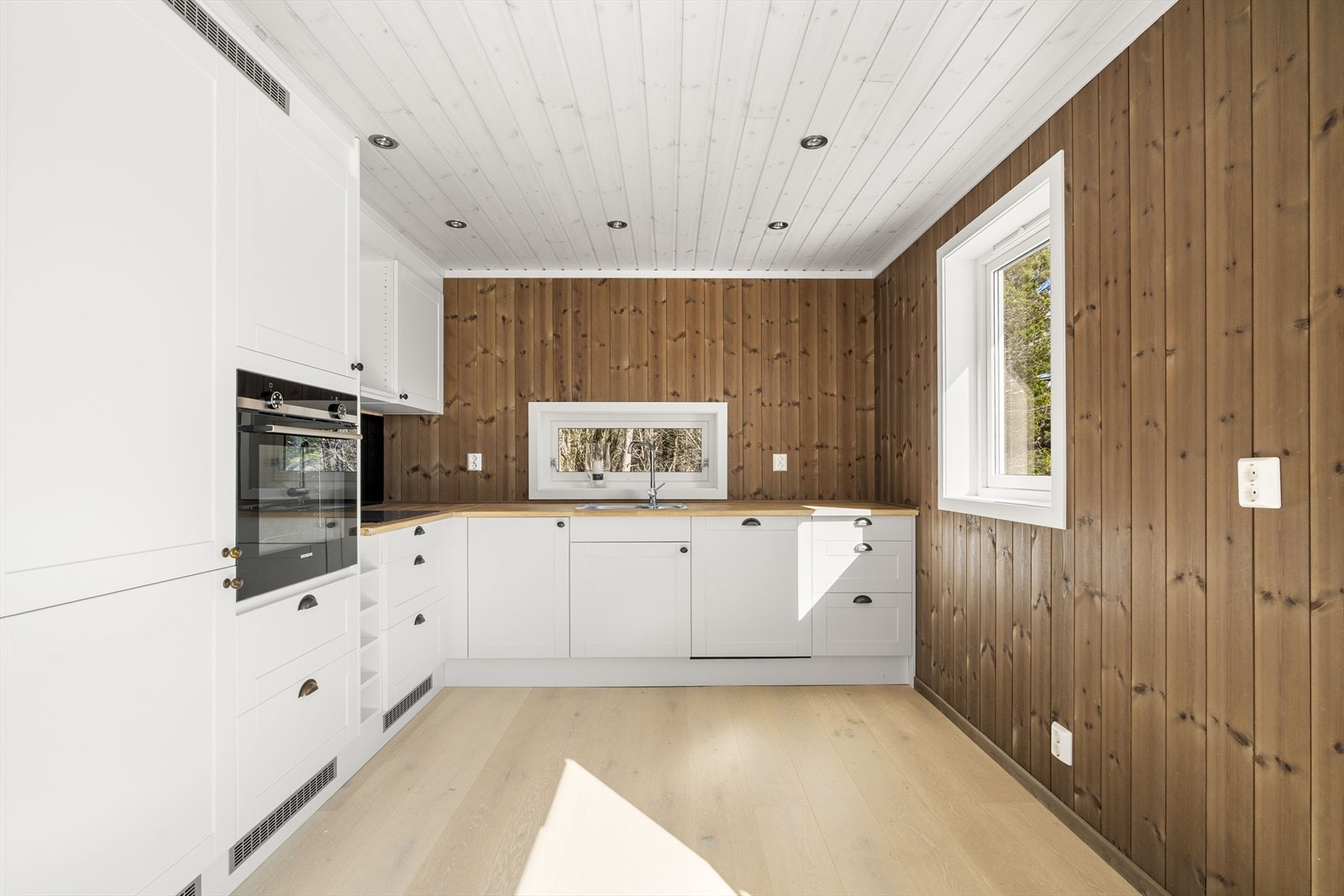 Romslig og innholdsrikt kjøkken med panel på vegger og i taket Galleribilde