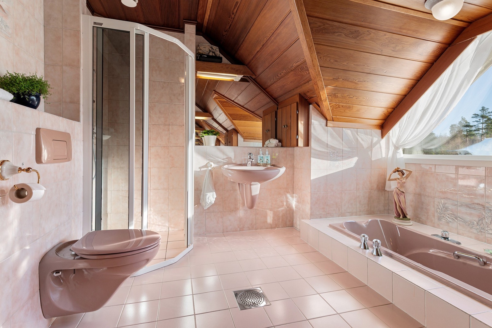 Pent baderom fra 1987 med vegghengt toalett, nedsenket badekar og dusjhjørne med skyvedører i glass. Galleribilde