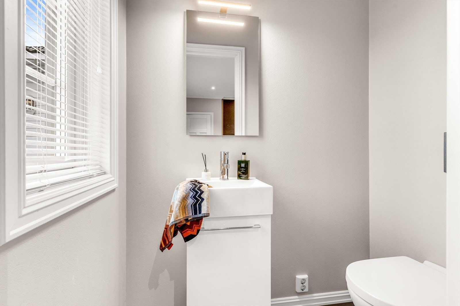 Toalettrommet har vegghengt toalett og porselensvask med synlig lekkasjesikring. Rommet er utstyrt med balansert ventilasjon. Galleribilde