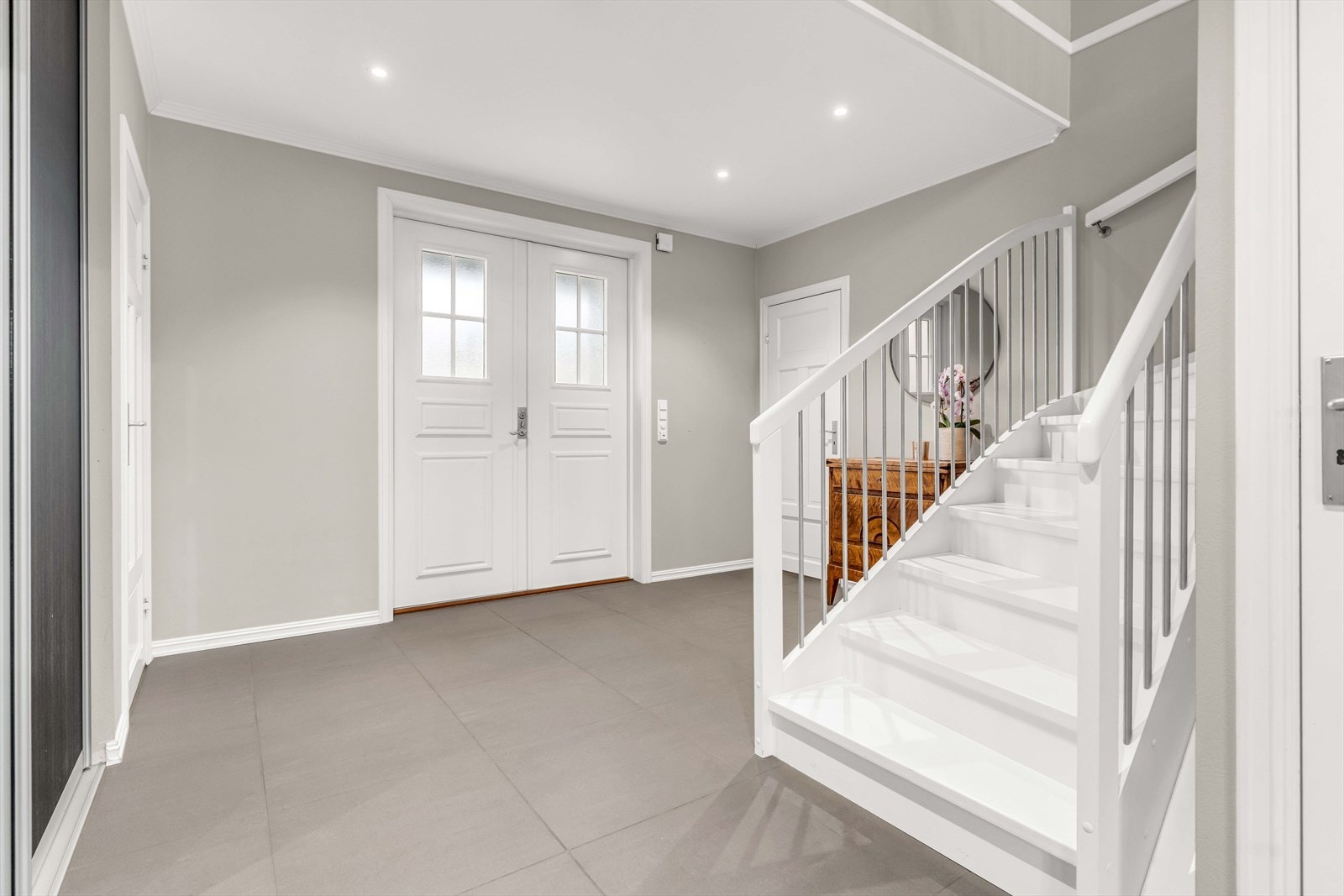 Hovedinngangen har doble dører som gir enkel og praktisk tilgang til boligen. Flislagt gulv, downlights i himlingen og god plass skaper en romslig og innbydende entré. Galleribilde