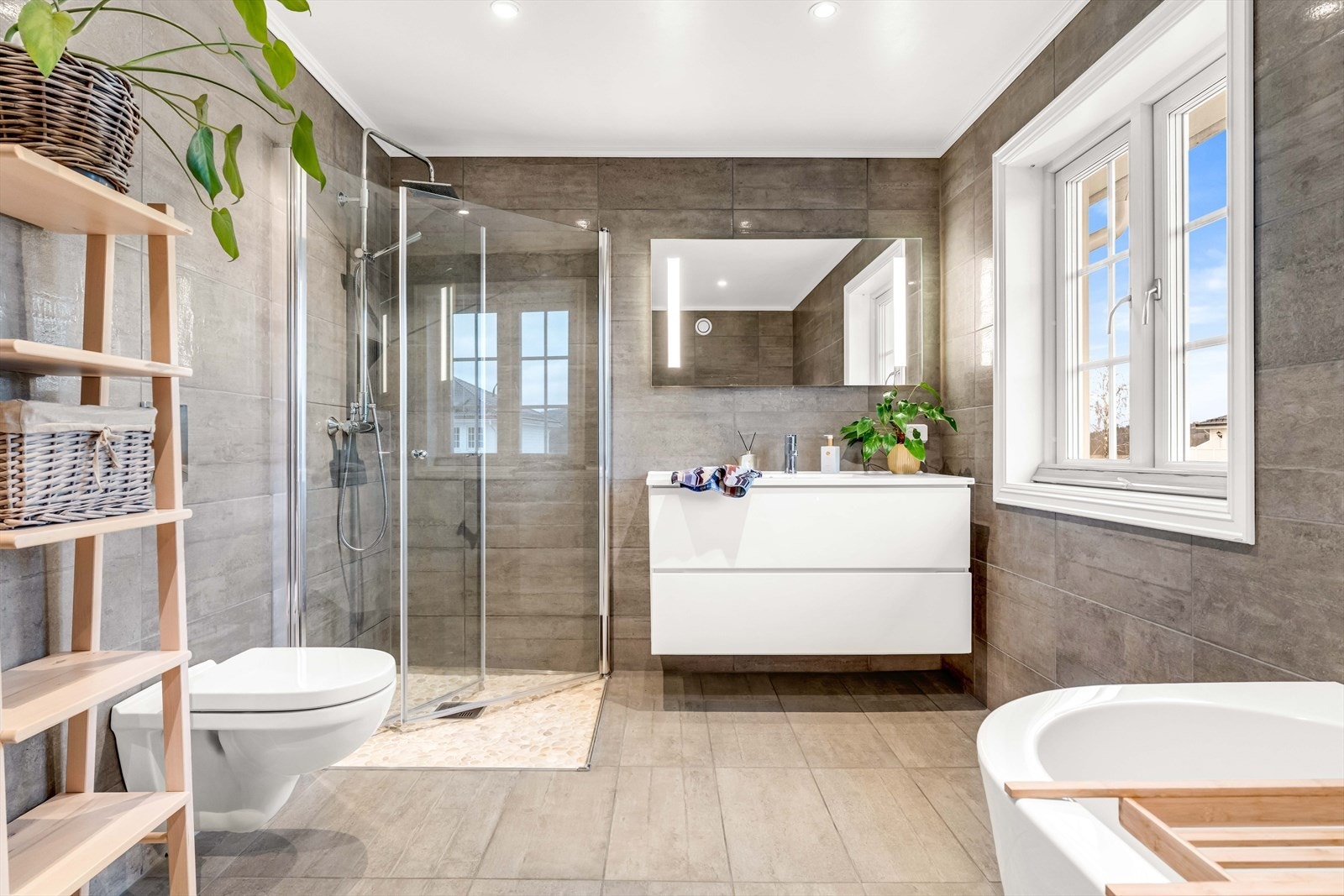 Lekkert og moderne bad med privat tilknytning til hovedsoverommet. Badet er innredet med badekar, vegghengt toalett, servant med skap, speil med belysning og en egen dusjsone med flotte detaljer. Galleribilde