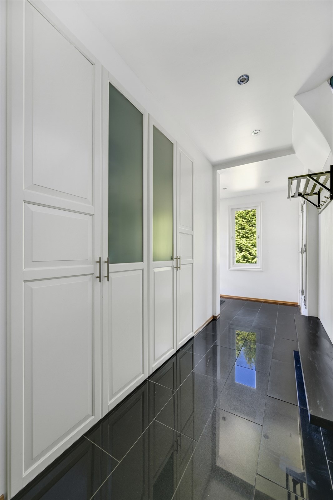 Du blir møtt av en stilren gang/entré med en stor og svært romslig innebygget garderobeløsning. Galleribilde