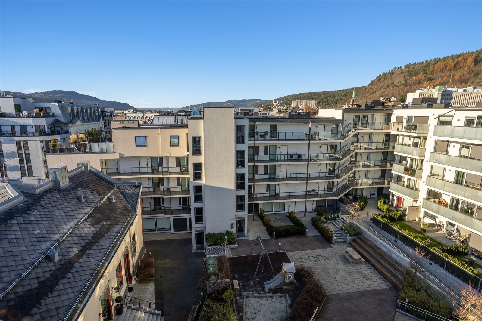 Pent opparbeidet felles uteareal med lekeapparater, sandkasse, sittebenker, utebelysning, steinbelagte trapper og asfalterte stier. Galleribilde