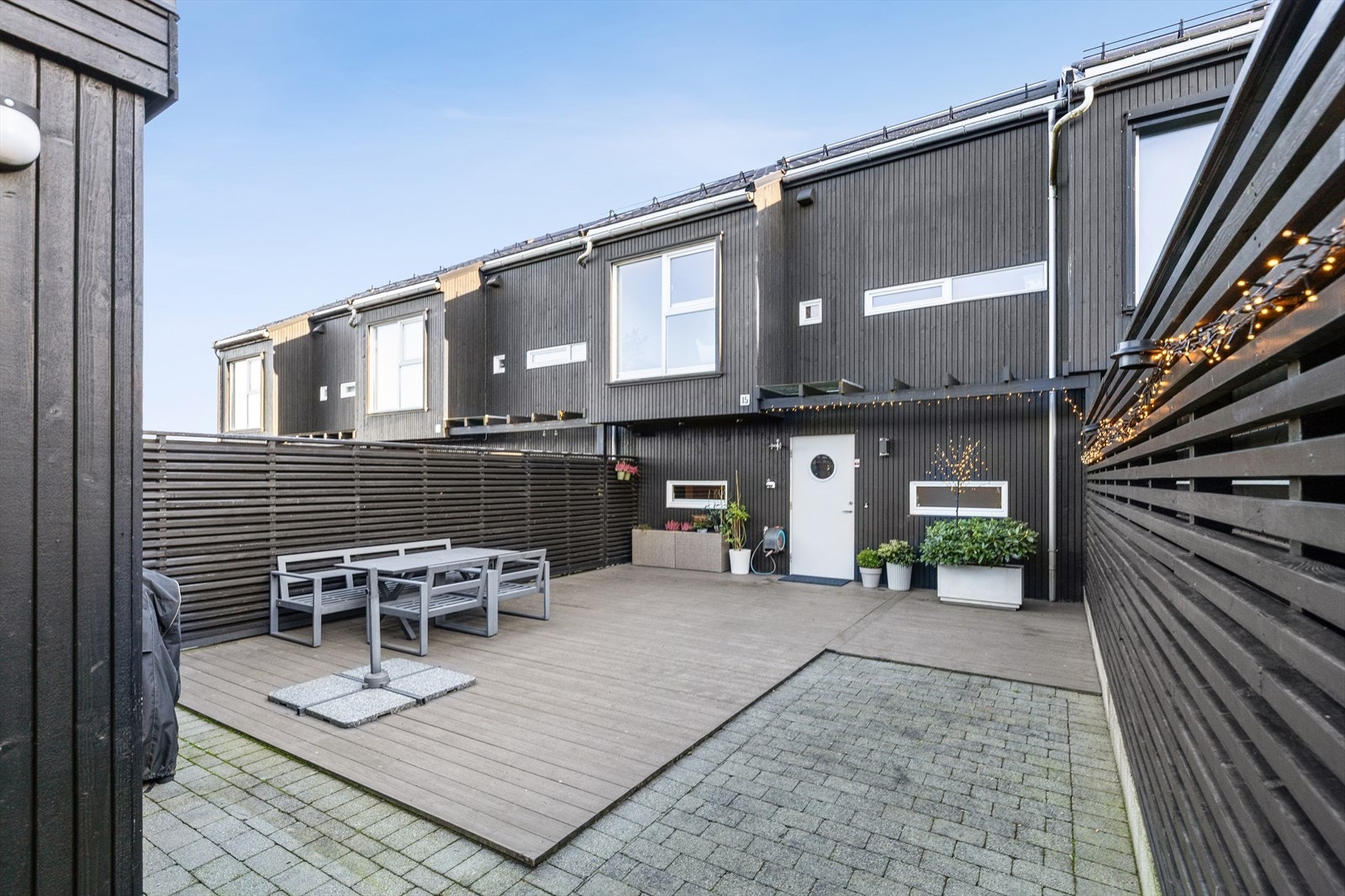 Mellom carporten og inngangspartiet er det en stor vestvendt uteplass med terrasse og brostein - I tillegg er det en østvendt terrasse utenfor stuen Galleribilde