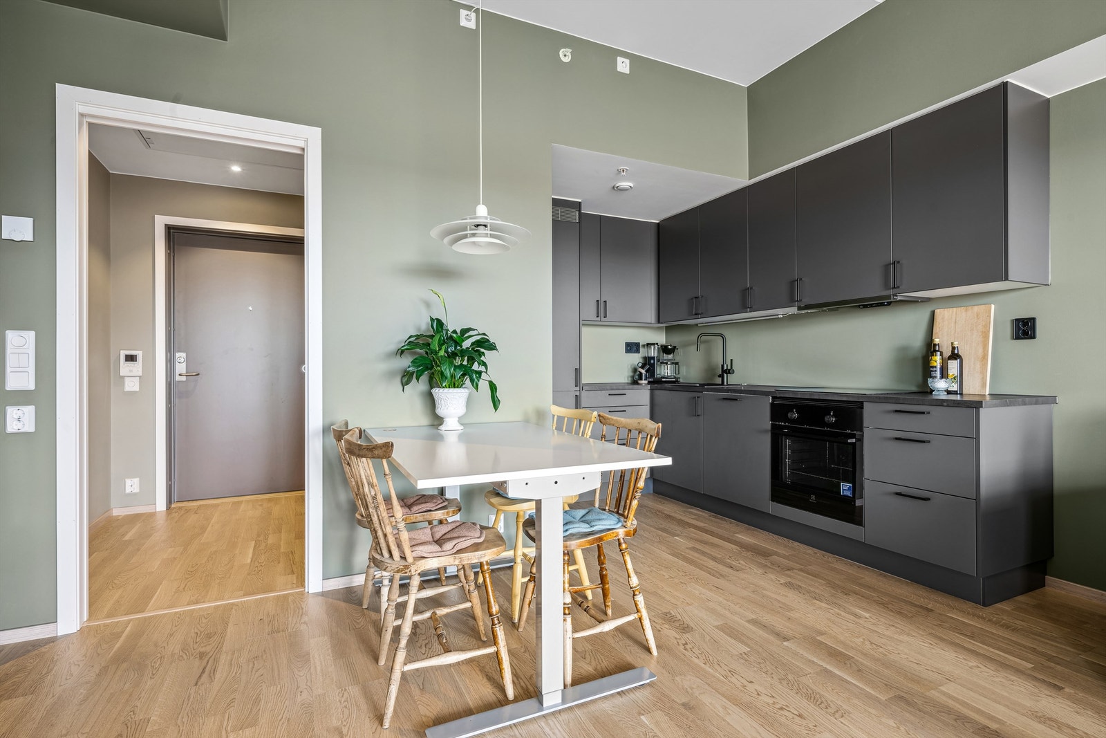 Pent kjøkken med innredning i glatte fronter, laminert benkeplate og integrerte hvitevarer Galleribilde