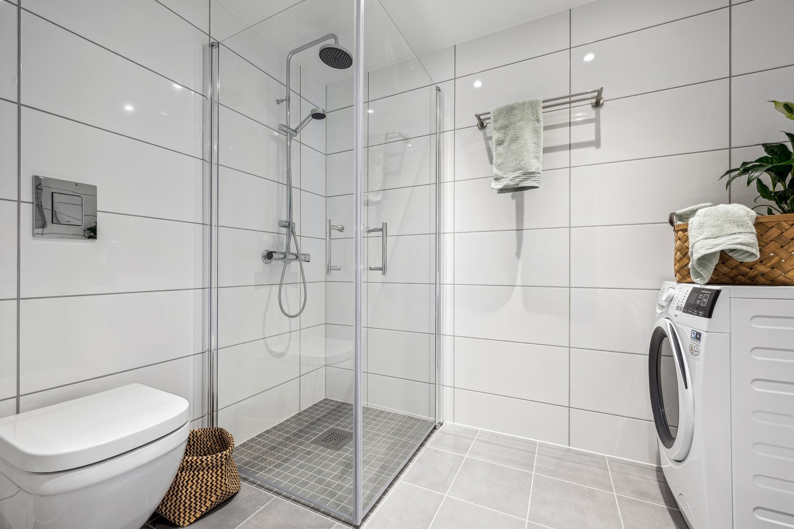 Badet er innredet med vegghengt toalett, dusjhjørne med glassdører og innredning med servant Galleribilde