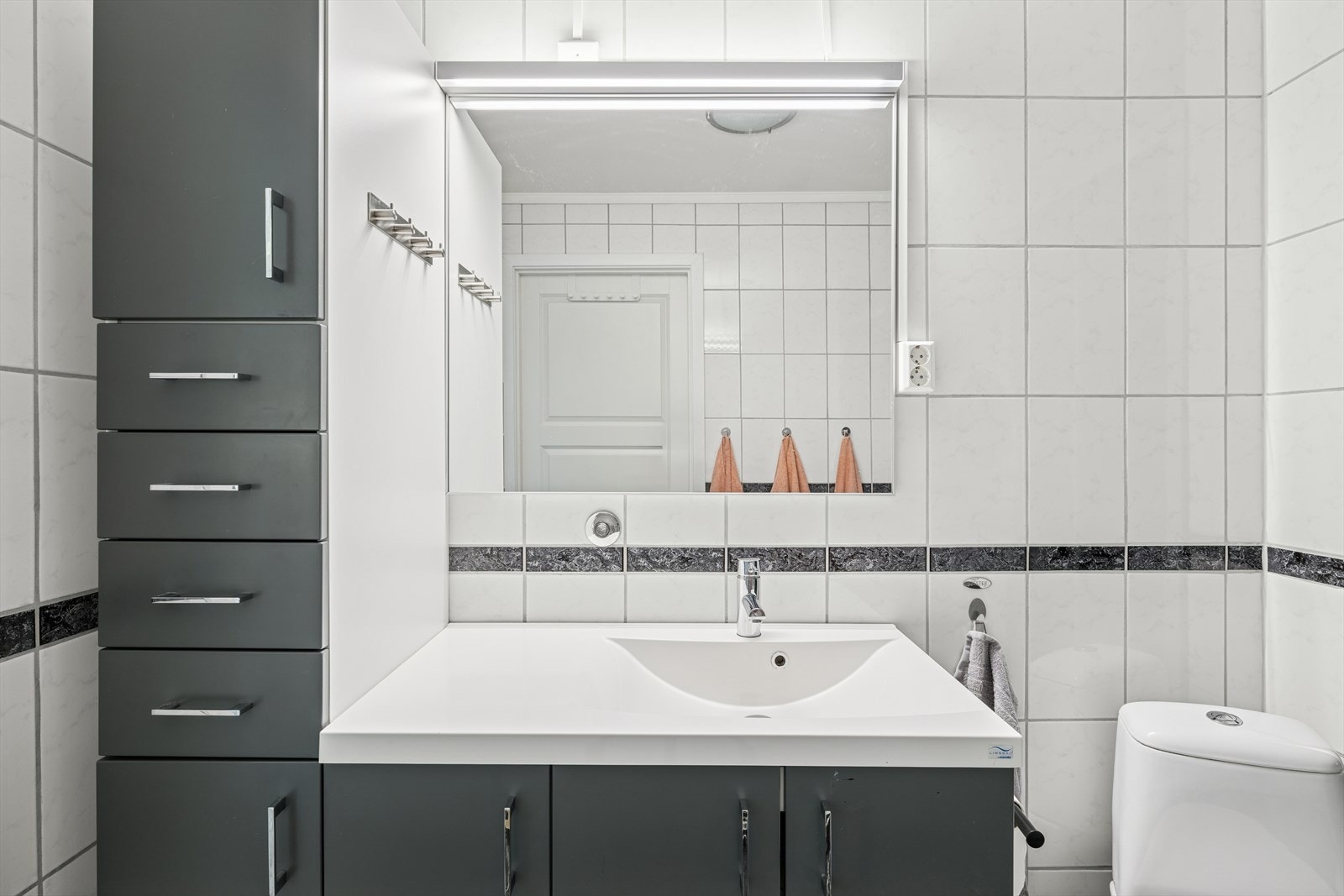 Badet er innredet med gulvstående toalett, servant og dusjkabinett. Det er plass og opplegg for vaskemaskin og tørketrommel. Galleribilde