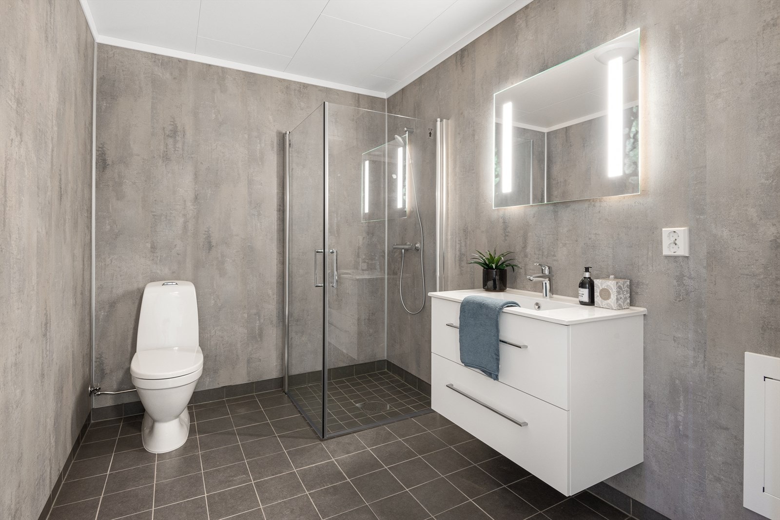 Bad med servantinnredning, toalett og dusjhjørne med innfellbare glassdører. Samt opplegg for vaskemaskin. Galleribilde