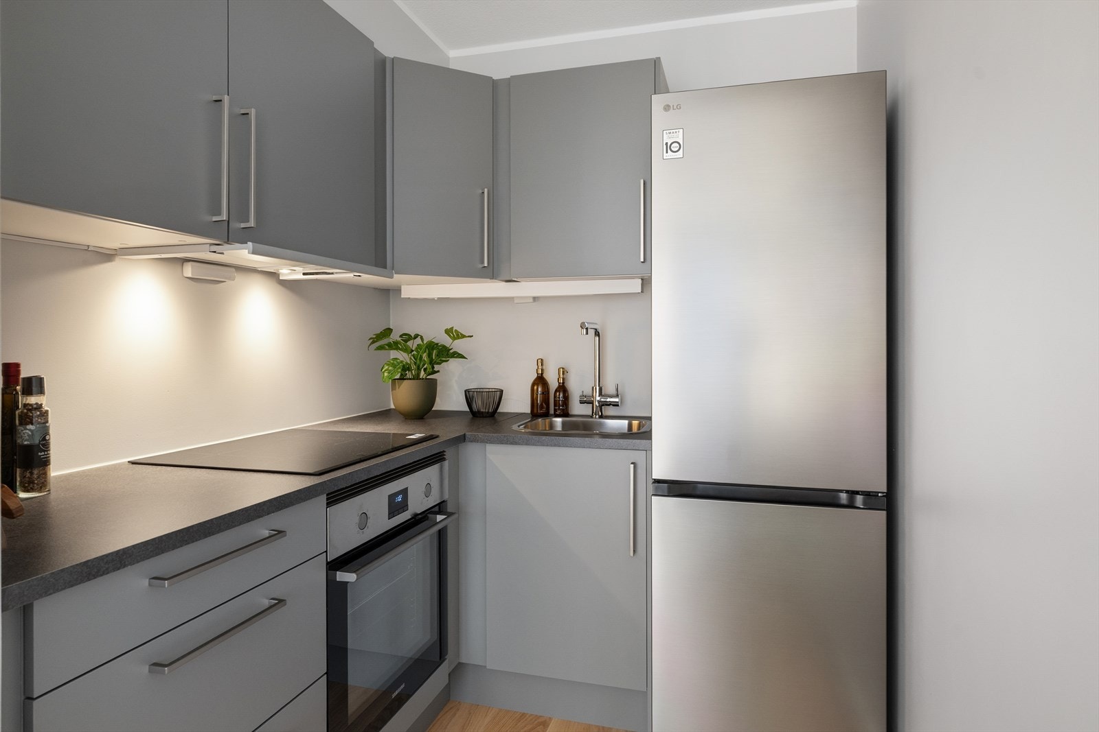 Moderne kjøkkeninnredning fra 2025 med slette fronter og laminatbenkeplater. Kjøkkenet har nedfelt stålkum med ettgreps blandebatteri Galleribilde