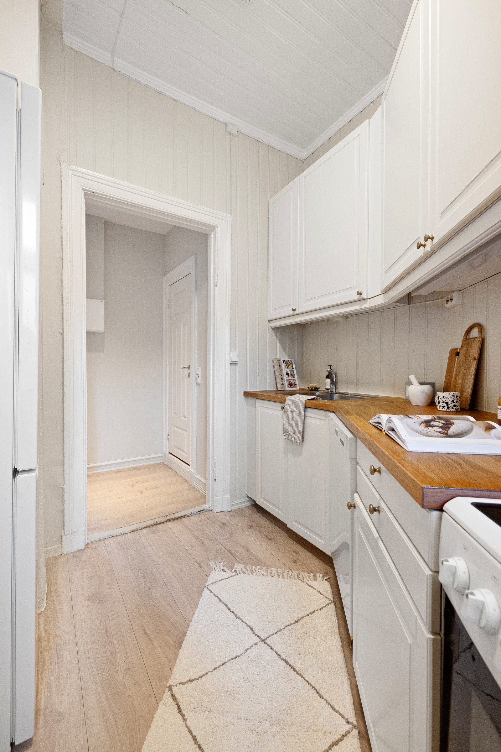 Benkeplaten er i heltre og gir god arbeidsplass langs hele kjøkkenbenken. Rommet er innredet med stekeovn, oppvaskmaskin og et frittstående kjøleskap. Galleribilde