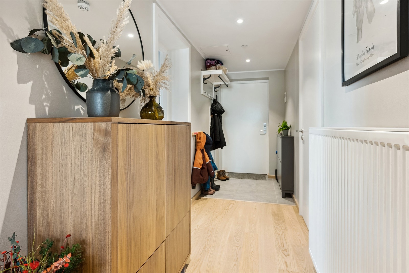 Velkommen inn i lys og pen entré med flislagte gulv med varme, lysemalte vegger og downlights i himling Galleribilde