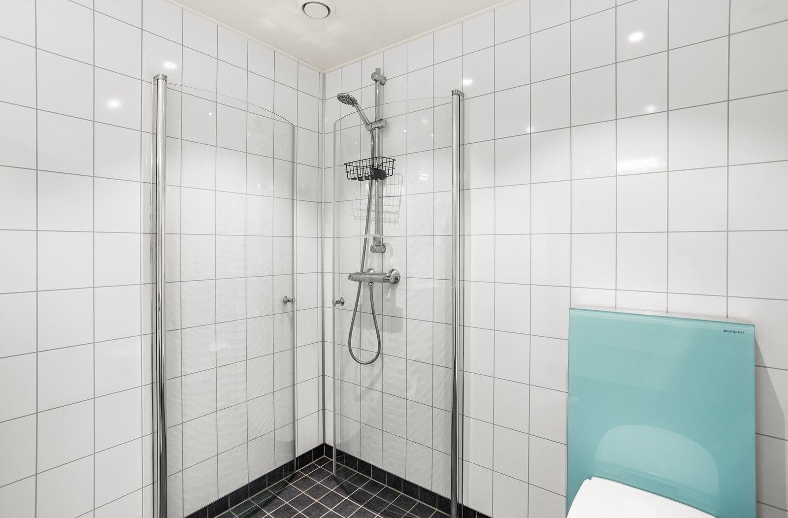 Badet er innredet med hvit servantinnredning med skuffeseksjon, speil, toalett, dusjhjørne og opplegg for vaskemaskin. Galleribilde