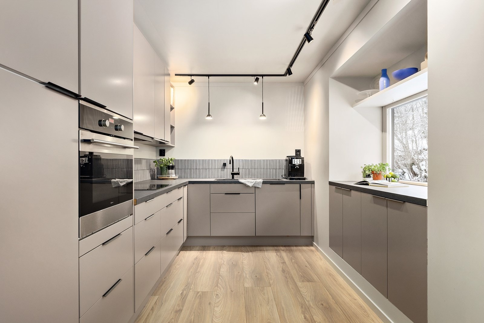 Kjøkkenet er oppusset i 2021 med slette fronter og mørk, laminert benkeplate. En stilren spotskinne gir godt, regulerbart lys over arbeidsflaten og fremhever de rene linjene i kjøkkenet. Galleribilde