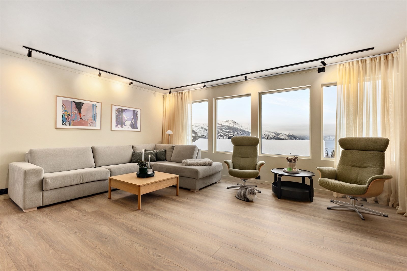 Den moderne stuen er et lyst og innbydende rom der store vindusflater slipper inn rikelig med dagslys og fremhever den vakre utsikten utenfor. Galleribilde